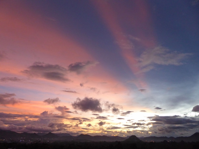 Reddish crepuscular rays over a twilight sky.