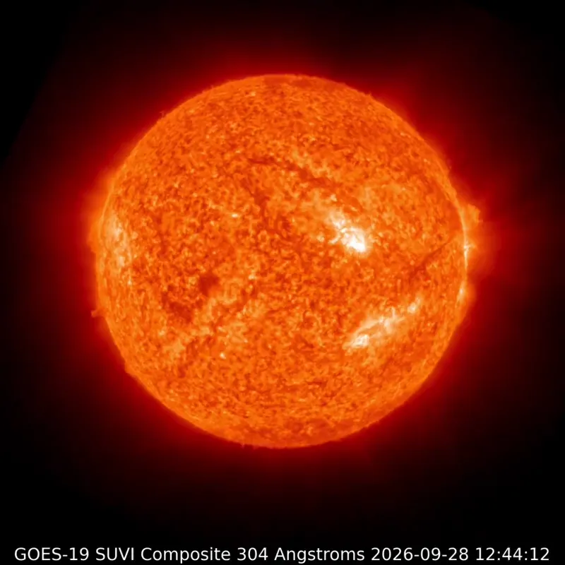 The sun is glowing orange-red in extreme ultraviolet light, with dark, snaking filaments across the disk and bright patches.
