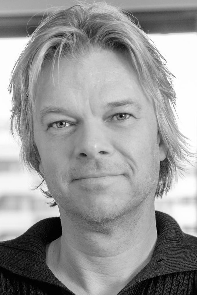 Black and white photo of a man with longish hair and scruffy beard.