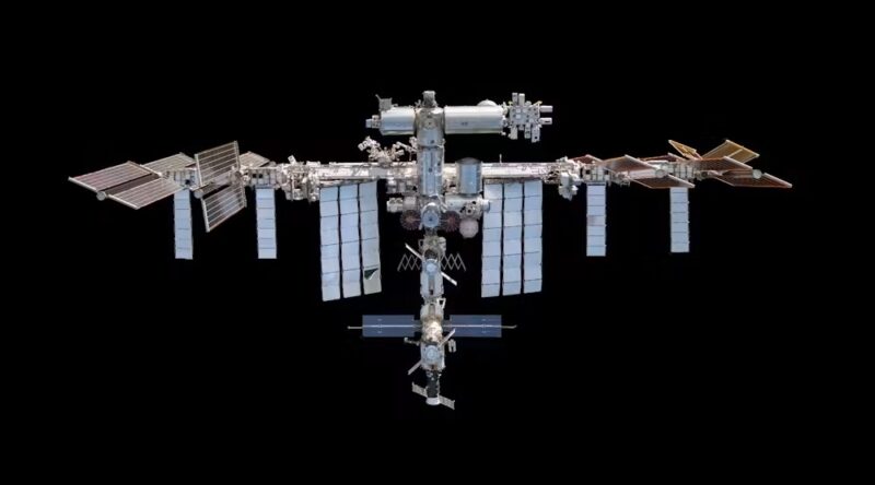 A metal structure made of numerous linked cylinders, with large solar panels, floating in black space.