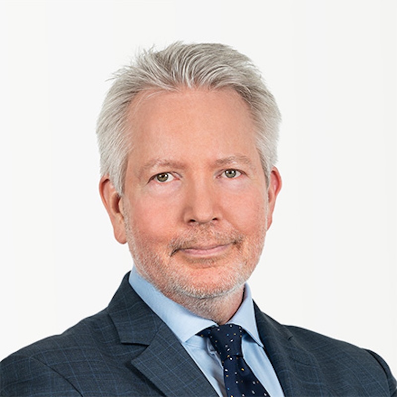 Smiling man with gray hair, wearing a suit and tie.