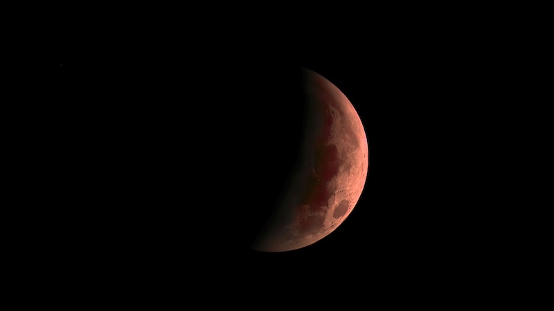 A partially eclipsed crimson moon where the moon's surface is about 2/3 covered with Earth's Shadow.