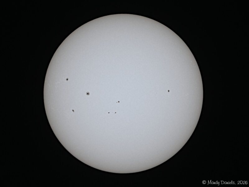 The sun, seen as a large white sphere with small dark spots.