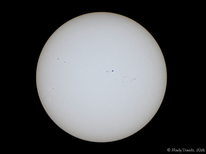 The sun, seen as a large white sphere with small dark spots.
