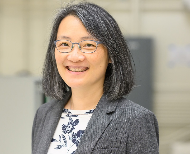 Smiling young woman with eyeglasses and straight pepper-and-salt hair.
