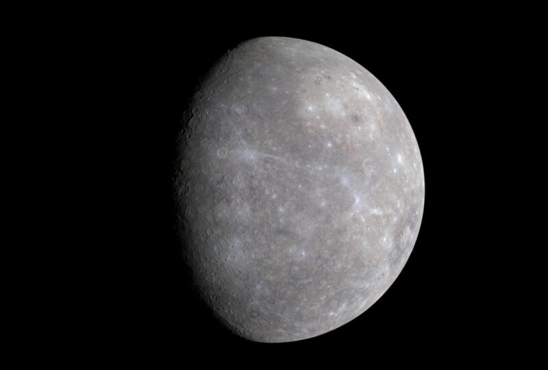 A cratered world, Mercury, in a gibbous phase on a dark background.