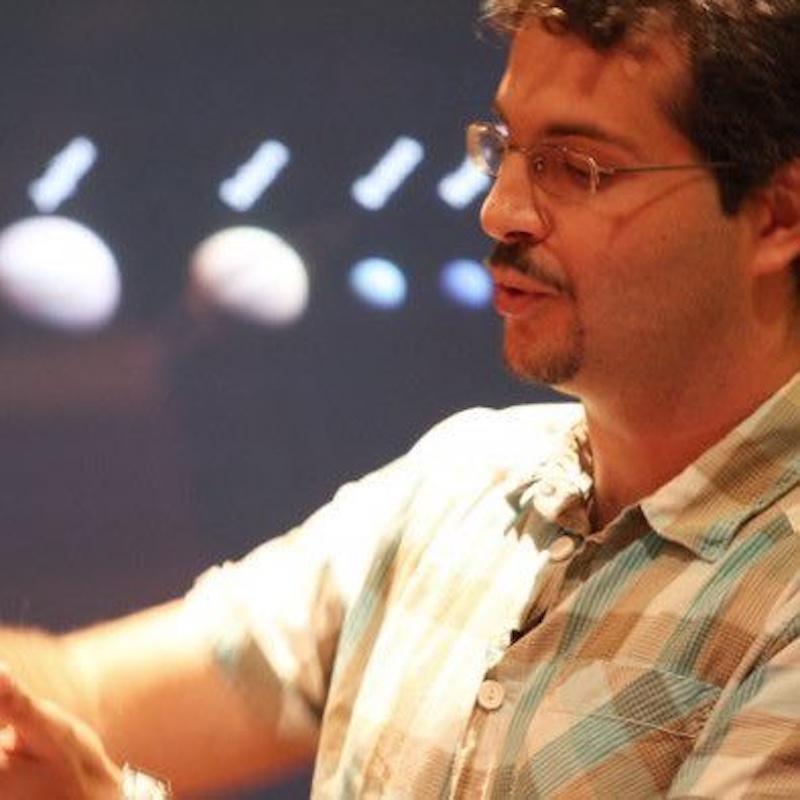 Man looking to the left, with 4 planets on a wall behind him.