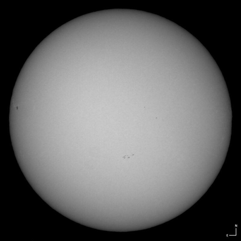 The sun, seen as a large white sphere with small dark spots.