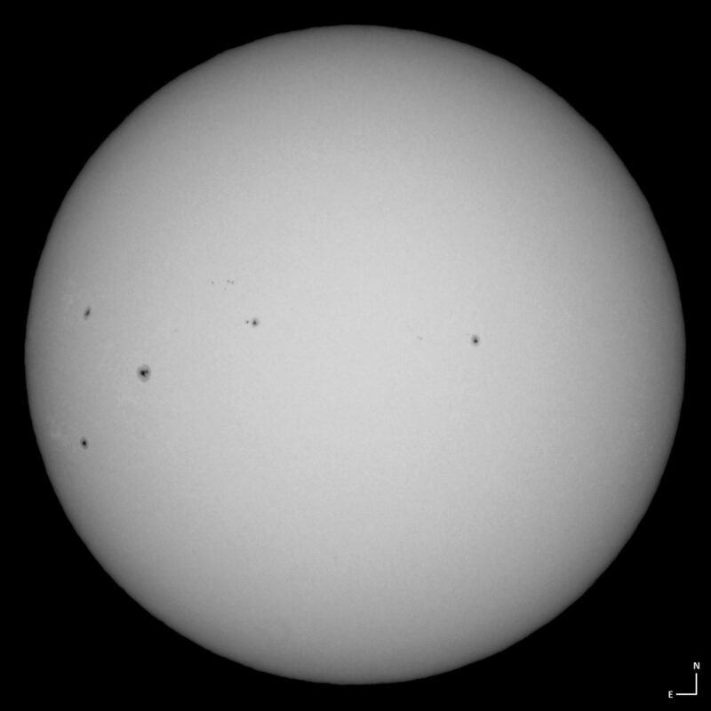 The sun, seen as a large white sphere with small dark spots.