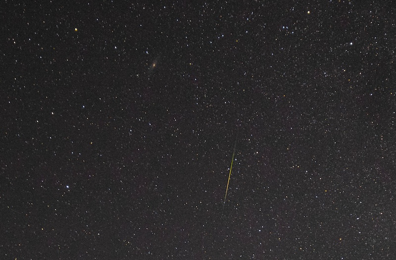 Starry sky with a colorful Perseid meteor and a smudge that's the Andromeda Galaxy.