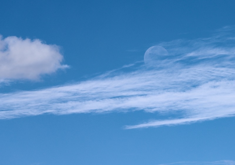 Waning gibbous moon partially hidden by clouds.