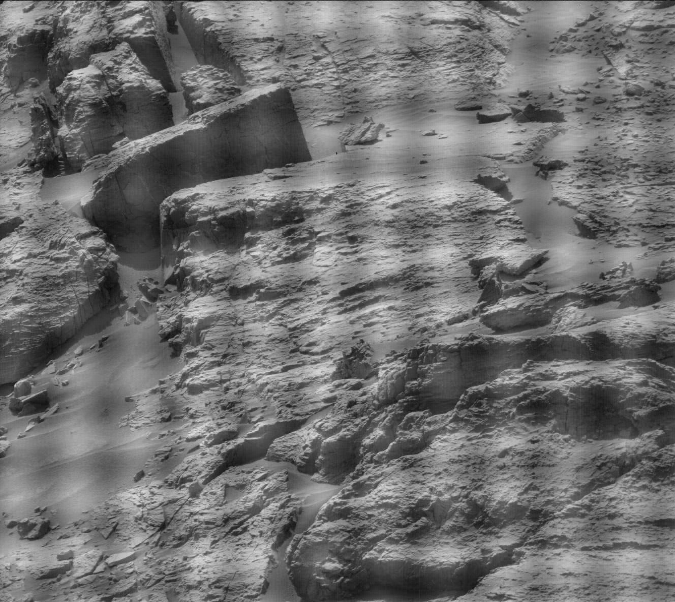 Mars image: Rocky ground with some sharp-edged rocks at upper right and what looks like a creature with a round head and rounded body.