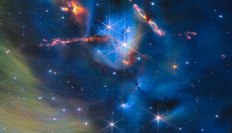Blue and yellow-green wispy background with spiky stars and orangish-red jets in different locations.