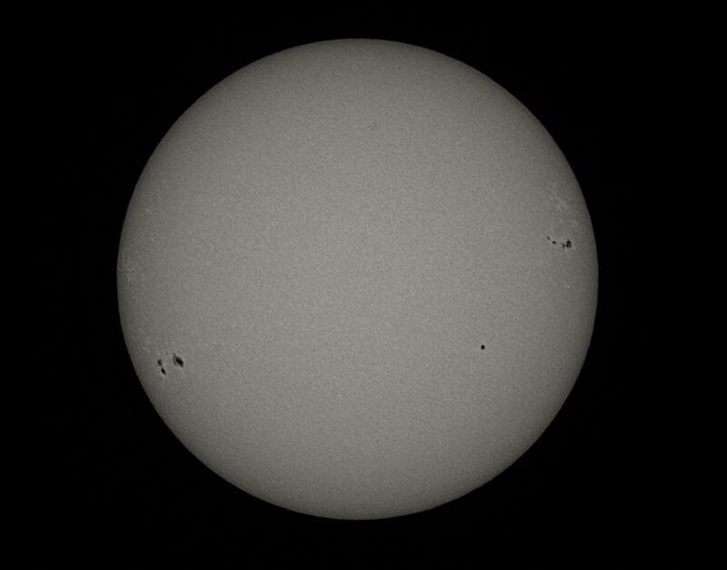 The sun, seen as a large gray sphere with small dark spots.