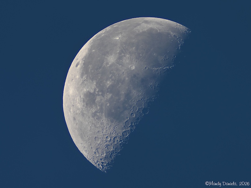 The last — or third quarter — moon against a dark blue day. Photo taken in daylight.