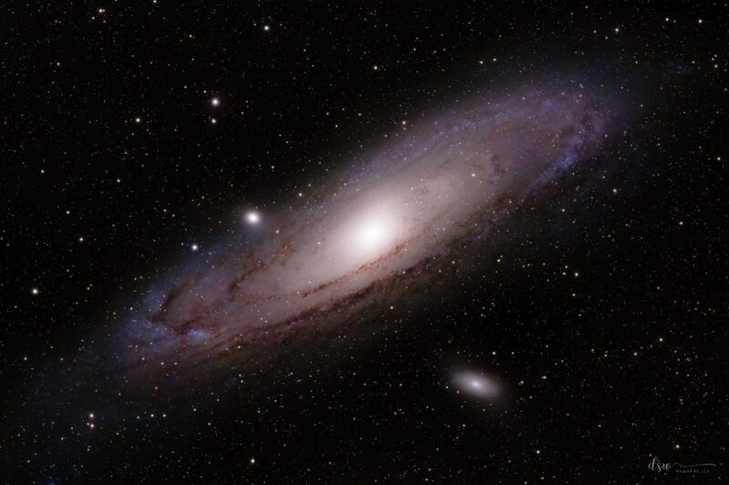 Large, pinkish, spiral-shaped object with thousands of foreground stars.