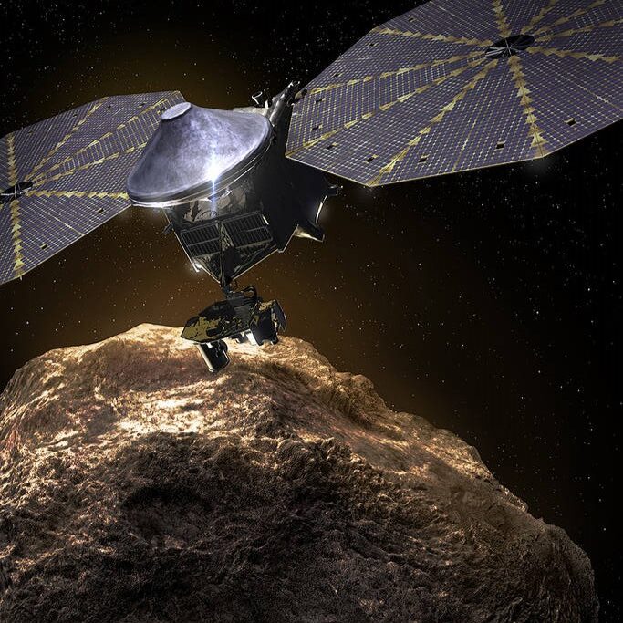 Lucy mission: Metal spacecraft with 2 round solar panels hovering close over a rocky body in space.