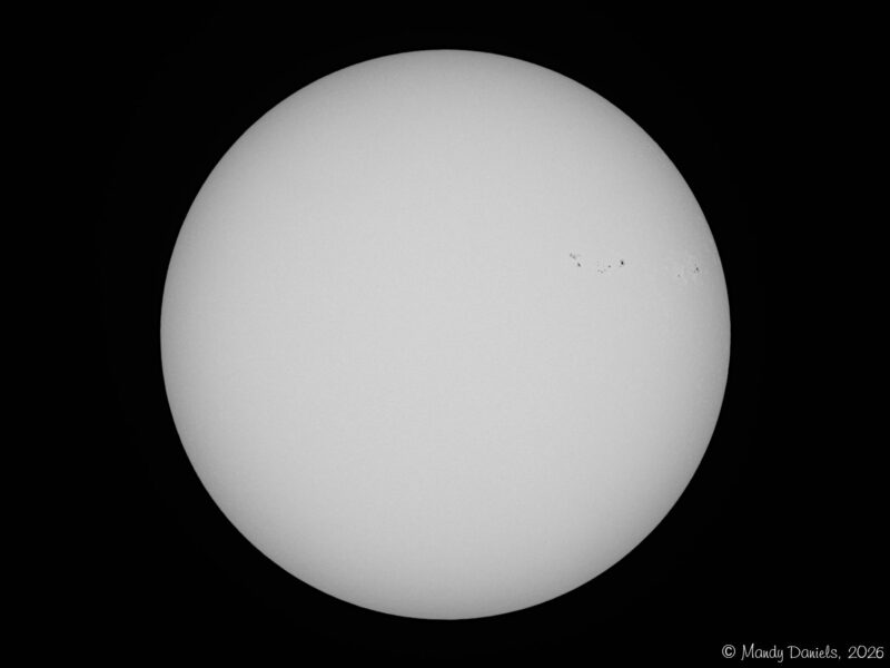 The sun, seen as a large white sphere with small dark spots.