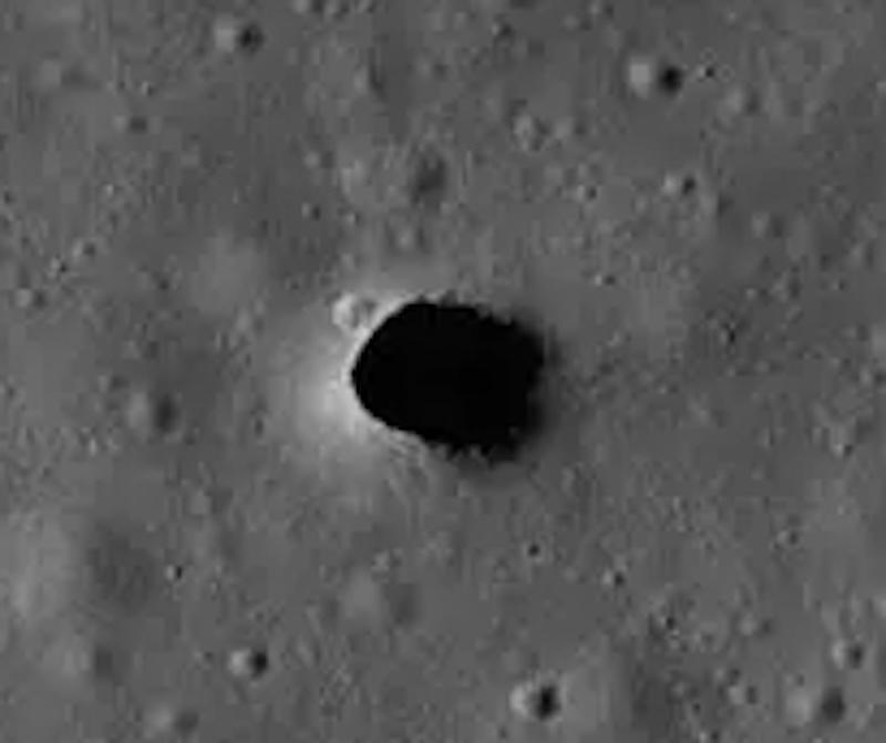 Searching for caves on the moon: Oval-shaped dark hole in gray terrain with craters around it, seen from above.