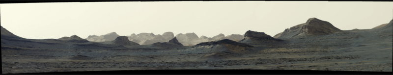Long, horizontal image of a craggy landscape with a yellowish-white sky.