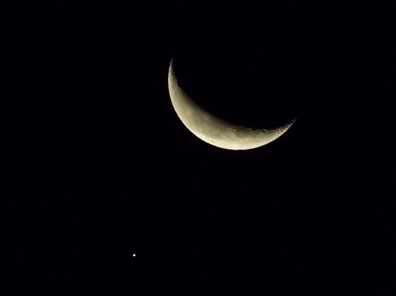 A crescent moon with a dot for Jupiter at lower left.