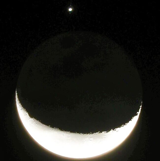A bright crescent moon with glowing dot for Jupiter above it, with tiny dots aligned in a line.
