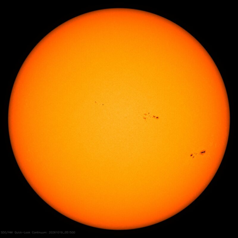 The sun in visible light, a yellow disk with a few small dark sunspots, each labeled with its active region number.