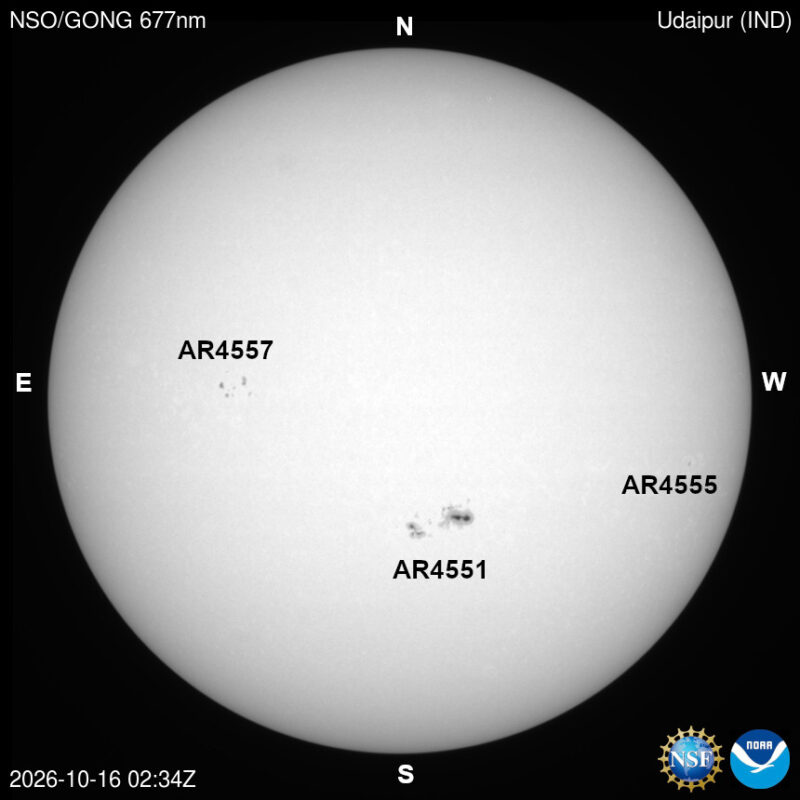 The sun, seen as a large white sphere with small dark spots.