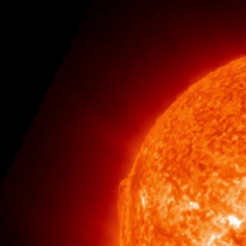 A glowing orange-red prominence arches above the sun's northeast edge against the black of space.