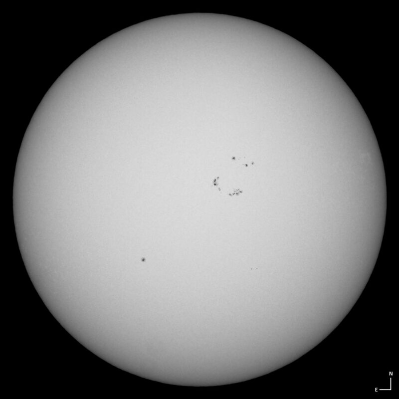 The sun, seen as a large white sphere with small dark spots.