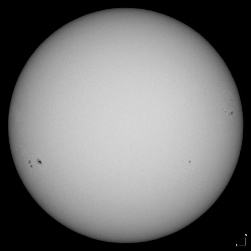 The sun, seen as a large white sphere with small dark spots.