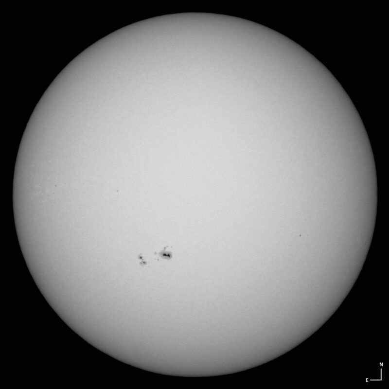 The sun, seen as a large white sphere with small dark spots.