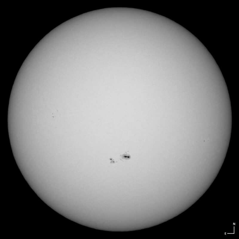 The sun, seen as a large white sphere with small dark spots.