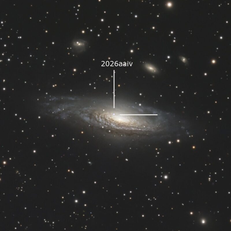 Large, yewllowish galaxy, a spiral seen almost edge-on, with white tick marks and numerous foreground stars.