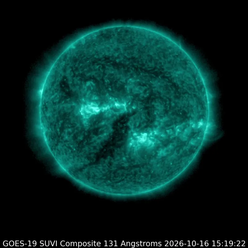 The sun glows teal in extreme ultraviolet, with a bright, brief flare erupting from a large active region.